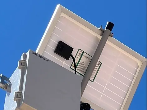 A solar-powered iLink gateway mounted on a pole against a blue sky